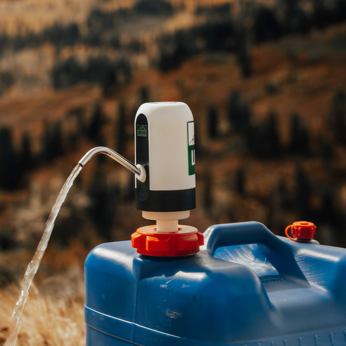 Reliance Aqua-Tainer water pump adapter kit dispensing water in the mountains
