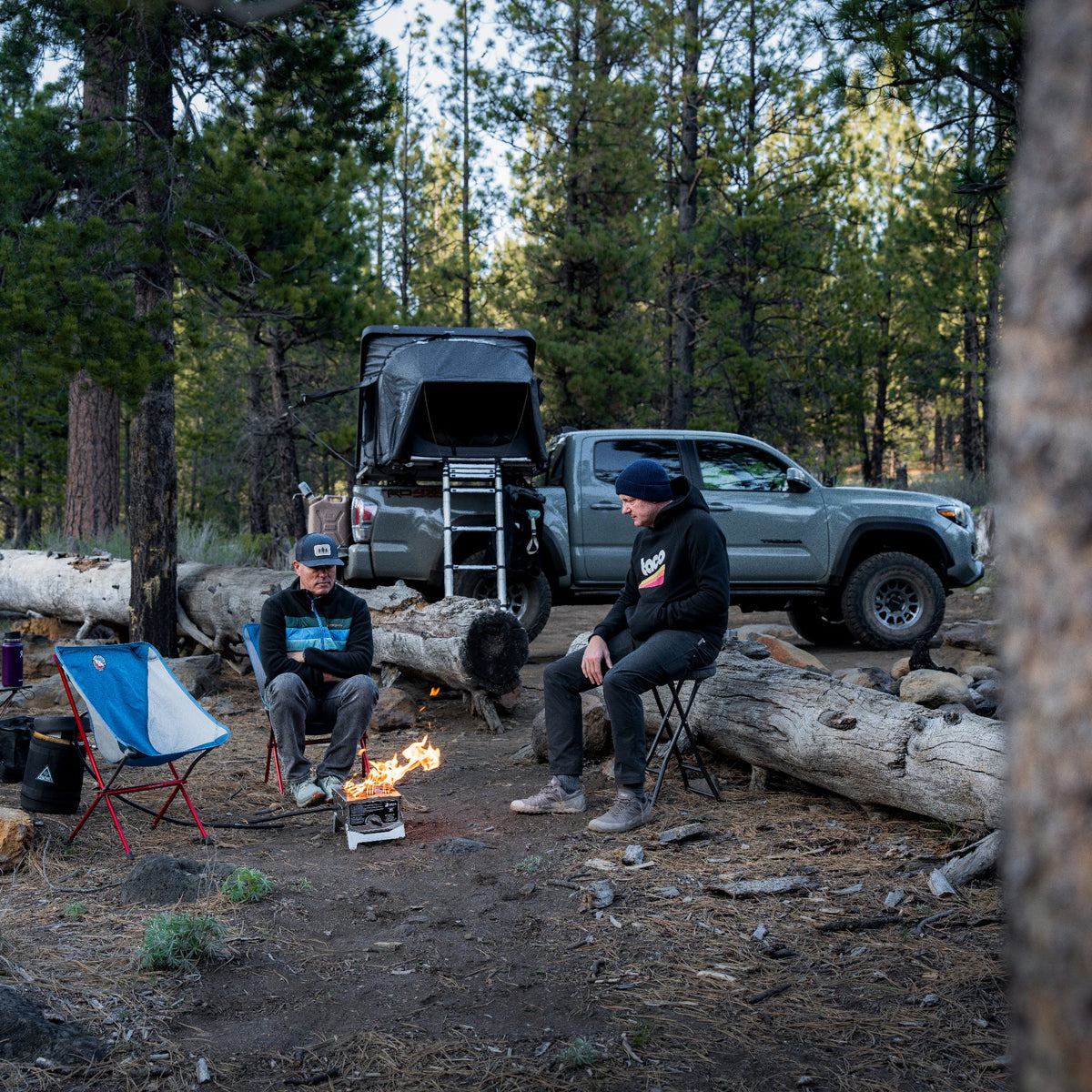 Two men sitting around a campfire in the woods